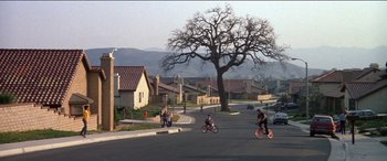 Movie still from “Poltergeist” (1982), directed by Tobe Hooper – A group of people riding bikes down a street; Extreme Wide shot, High angle