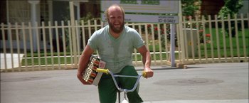 Movie still from “Poltergeist” (1982), directed by Tobe Hooper – A man riding a bike with a beer case on the back of it; Medium shot, Low angle
