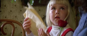 Movie still from “Poltergeist” (1982), directed by Tobe Hooper – A little girl holding a piece of bread and eating a piece of cake; Close Up shot, Over the shoulder angle