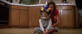 Movie still from “Poltergeist” (1982), directed by Tobe Hooper – A young boy wearing a football helmet sits on the floor; Medium shot, High angle