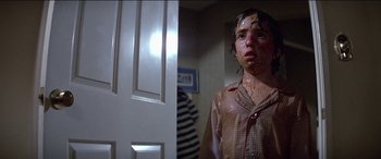 Movie still from “Poltergeist” (1982), directed by Tobe Hooper – A person with a pie in their mouth standing in front of a door; Close Up shot, Low angle