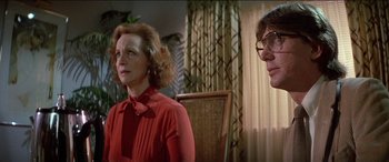 Movie still from “Poltergeist” (1982), directed by Tobe Hooper – A woman in a red dress and a man in glasses; Close Up shot, Low angle