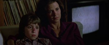Movie still from “Poltergeist” (1982), directed by Tobe Hooper – A woman and a boy sitting next to each other in a room; Close Up shot, Low angle