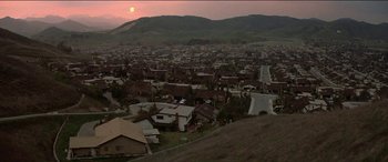 Movie still from “Poltergeist” (1982), directed by Tobe Hooper – An aerial view of a town with a sunset in the background; Extreme Wide shot, High angle