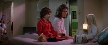 Movie still from “Poltergeist” (1982), directed by Tobe Hooper – A woman and a boy sitting on a bed playing a video game; Medium shot, Over the shoulder angle