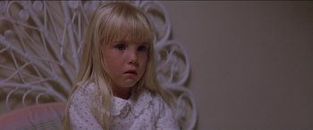 Movie still from “Poltergeist” (1982), directed by Tobe Hooper – A little girl with blonde hair sitting in front of a white wall; Close Up shot, High angle