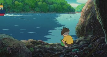 Movie still from “Ponyo” (2008), directed by Hayao Miyazaki – A boy sitting on the ground near a body of water; Wide shot, High angle
