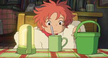 Movie still from “Ponyo” (2008), directed by Hayao Miyazaki – A little girl sitting at a table drinking from a green cup; Medium shot, High angle
