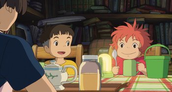 Movie still from “Ponyo” (2008), directed by Hayao Miyazaki – Two children are sitting at a table with a jar of honey; Medium shot, Over the shoulder angle