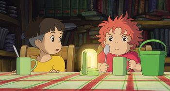 Movie still from “Ponyo” (2008), directed by Hayao Miyazaki – Two children are sitting at a table with a cup of tea; Medium shot, High angle