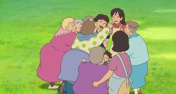 Movie still from “Ponyo” (2008), directed by Hayao Miyazaki – A group of people standing around each other in the grass; Medium shot, High angle