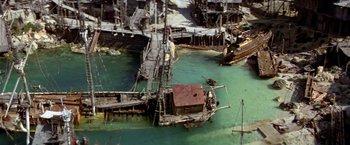 Movie still from “Popeye” (1980), directed by Robert Altman – An aerial view of an old boat in the water; Extreme Wide shot, High angle