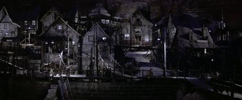 Movie still from “Popeye” (1980), directed by Robert Altman – A stage set for a play with a lot of lighting; Extreme Wide shot, High angle