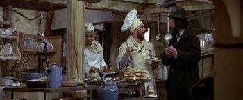 Movie still from “Popeye” (1980), directed by Robert Altman – A group of men standing in a kitchen preparing food; Medium shot, High angle