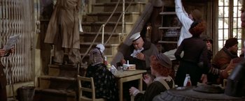 Movie still from “Popeye” (1980), directed by Robert Altman – A group of people sitting at a table eating food; Wide shot, High angle