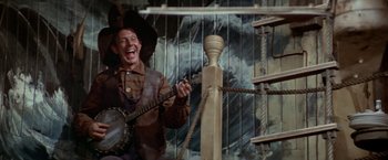 Movie still from “Popeye” (1980), directed by Robert Altman – A man holding a guitar and laughing; Medium shot, Low angle