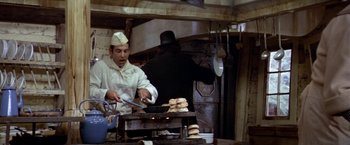 Movie still from “Popeye” (1980), directed by Robert Altman – A man in a chef's outfit cooking hamburgers in a kitchen; Medium shot, High angle
