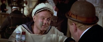 Movie still from “Popeye” (1980), directed by Robert Altman – A man in a sailor's uniform with a bandage on his face; Close Up shot, Over the shoulder angle