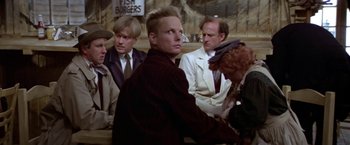 Movie still from “Popeye” (1980), directed by Robert Altman – A group of people sitting around a table; Medium shot, Over the shoulder angle