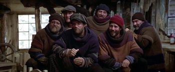 Movie still from “Popeye” (1980), directed by Robert Altman – A group of men sitting next to each other; Medium shot, High angle