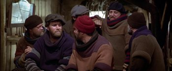 Movie still from “Popeye” (1980), directed by Robert Altman – A group of men sitting next to each other; Medium shot, High angle