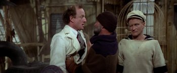 Movie still from “Popeye” (1980), directed by Robert Altman – Two men talking to each other in front of a cage; Medium shot, Over the shoulder angle