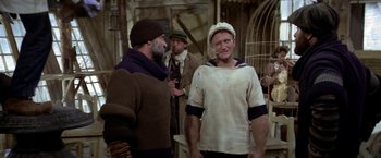 Movie still from “Popeye” (1980), directed by Robert Altman – A group of men standing next to each other in a room; Medium shot, High angle