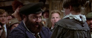Movie still from “Popeye” (1980), directed by Robert Altman – A man with a long beard is smiling at a crowd of people; Close Up shot, Over the shoulder angle