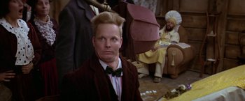 Movie still from “Popeye” (1980), directed by Robert Altman – A man in a suit and bow tie with an umbrella in his hair; Close Up shot, Low angle