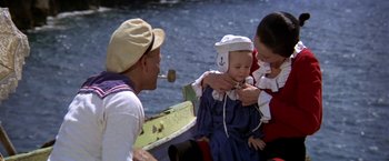 Movie still from “Popeye” (1980), directed by Robert Altman – A man holding a baby while a woman holds another baby; Medium shot, High angle