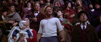 Movie still from “Popeye” (1980), directed by Robert Altman – A crowd of people sitting in a room watching something; Medium shot, Low angle