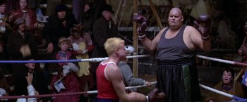 Movie still from “Popeye” (1980), directed by Robert Altman – A man wearing boxing gloves in a boxing ring; Wide shot, Low angle