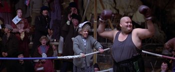 Movie still from “Popeye” (1980), directed by Robert Altman – An old woman in a boxing ring with a man in a boxing glove; Wide shot, Low angle