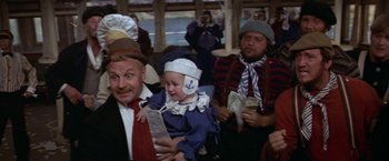 Movie still from “Popeye” (1980), directed by Robert Altman – A group of people sitting in a room; Medium shot, High angle