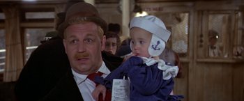 Movie still from “Popeye” (1980), directed by Robert Altman – A man holding a baby while wearing a hat; Close Up shot, High angle