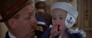 Movie still from “Popeye” (1980), directed by Robert Altman – An older man holding a baby in his hand; Close Up shot, Over the shoulder angle