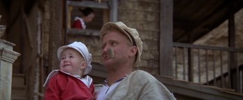 Movie still from “Popeye” (1980), directed by Robert Altman – A man and a child are sitting together; Close Up shot, Low angle