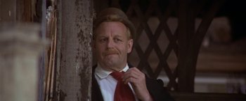 Movie still from “Popeye” (1980), directed by Robert Altman – A man in a suit and tie holding a red tie; Close Up shot, Low angle