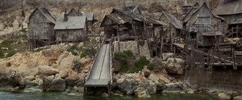 Movie still from “Popeye” (1980), directed by Robert Altman – An old house with a slide going down the side of it; Extreme Wide shot, High angle