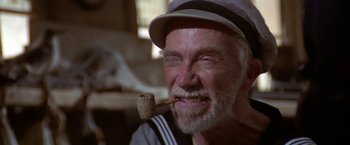 Movie still from “Popeye” (1980), directed by Robert Altman – An older man with a pipe in his mouth; Close Up shot, Low angle