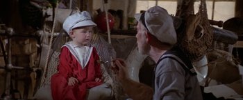 Movie still from “Popeye” (1980), directed by Robert Altman – An older man and a young boy sitting on a swing; Medium shot, Over the shoulder angle