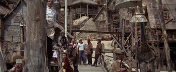 Movie still from “Popeye” (1980), directed by Robert Altman – A group of people standing on top of a wooden platform; Wide shot, Low angle