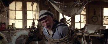 Movie still from “Popeye” (1980), directed by Robert Altman – An old man in a sailor's outfit yawns while tied to ropes; Medium shot, High angle