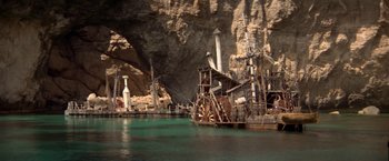 Movie still from “Popeye” (1980), directed by Robert Altman – A boat in the middle of a lake near a cave; Extreme Wide shot, High angle