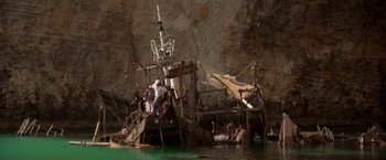 Movie still from “Popeye” (1980), directed by Robert Altman – A group of people sitting on top of a boat in the water; Extreme Wide shot, High angle