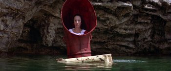 Movie still from “Popeye” (1980), directed by Robert Altman – A woman sitting in a red barrel in the middle of a body of water; Wide shot, High angle