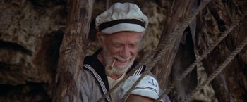 Movie still from “Popeye” (1980), directed by Robert Altman – An old man in a sailor's outfit smoking a pipe; Medium shot, High angle