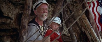 Movie still from “Popeye” (1980), directed by Robert Altman – An old man and a young boy are standing next to each other; Medium shot, Low angle