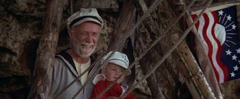 Movie still from “Popeye” (1980), directed by Robert Altman – An older man and a young boy are smiling; Medium shot, Low angle