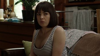 Movie still from “Glitch” (2015), created by Tony Ayres – A woman sitting on a couch in front of a window; Close Up shot, Over the shoulder angle